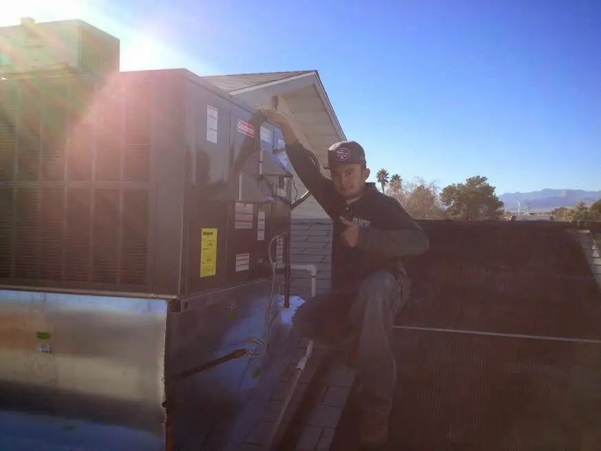 HVAC technician performing AC Tune-Up on a rooftop unit in Syracuse
